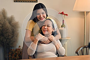 Portrait of a beautiful young Asian woman smiling and hugging her middle aged mom