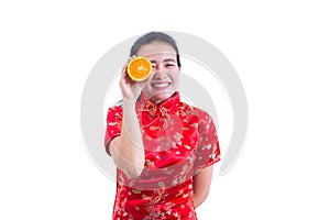 Portrait of Beautiful Young asian woman wear chinese dress traditional cheongsam. holding orange slices in front of her eye