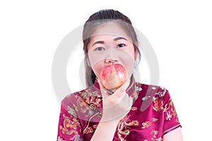 Portrait of Beautiful Young asian woman wear chinese dress traditional cheongsam or qipao. Eating red apple,