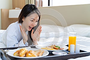 Portrait beautiful young Asian woman wearing bathrobe enjoy breakfast on a bed