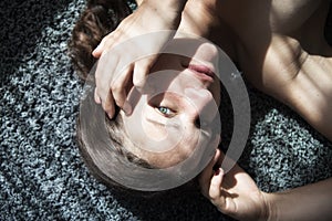 Portrait of a beautiful young attractive sexy woman, lying on carpet, partially with shadows of a string curtain