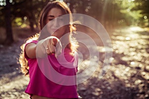 Portrait of beautiful young blinking woman against the sun background