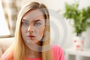 Portrait of beautiful young blond woman sit on sofa in room early morning