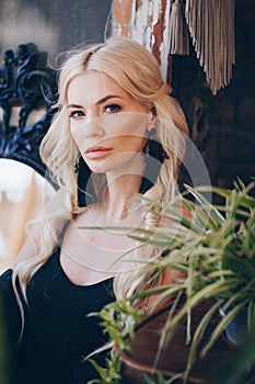 Portrait of beautiful young blonde in the black clothing of style of boho in a summer arbour