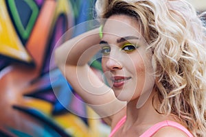 Portrait of beautiful young blonde caucasian woman near wall with graffiti. Outdoors