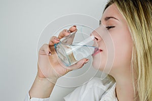 Portrait of a beautiful young blonde woman drinking a glass of water