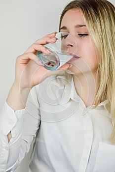 Portrait of a beautiful young blonde woman drinking a glass of water