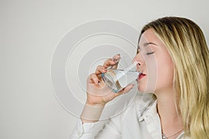 Portrait of a beautiful young blonde woman drinking a glass of water