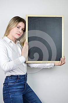 Portrait of a beautiful young blonde woman holding a blank whiteboard at shoulder height with room to add text