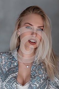 Portrait of a beautiful young blonde woman with natural make-up with blue eyes with sexy lips in a vintage shirt with a pattern