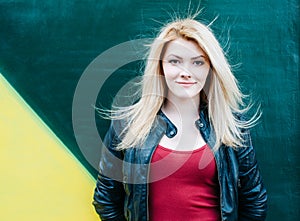 Portrait of a beautiful young blonde woman near green wall. Blowing Long Hair.