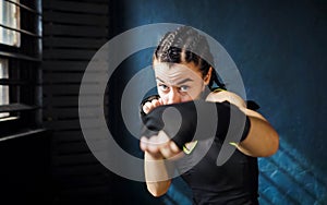 Portrait beautiful young boxing woman training punching in gym