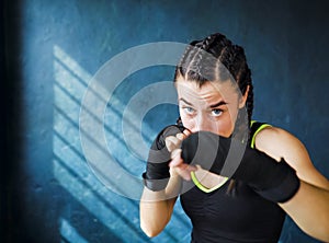 Portrait beautiful young boxing woman training punching in gym free space, copyspace