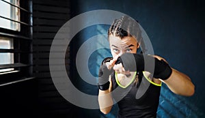 Portrait beautiful young boxing woman training punching in gym free space, copyspace