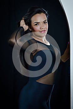 Portrait of a beautiful young Brazilian woman dressed in a skintight bodysuit fixing her hair seductively