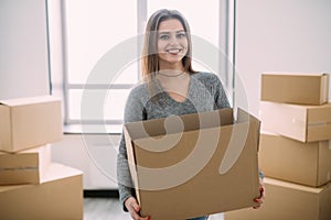 Portrait of beautiful young brunette packing carrying some boxes to move into her new home