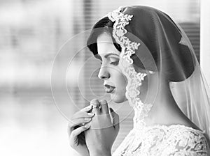 Portrait of beautiful young brunette sensual pensive bride in white lace dress and veil on head. Dream girl. Young bride