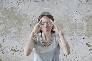 Portrait of beautiful young brunette touching her temples feeling stress