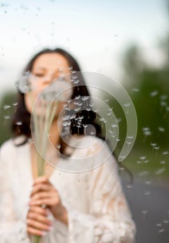 Portrait of beautiful young brunette woman with dandelion flowers on the rural asphalt road