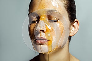 Portrait of beautiful young brunette woman with freckles and honey on face with closed eyes and serious face