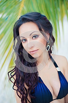 Portrait of a beautiful young brunette woman with long curly hair against a background of exotic nature