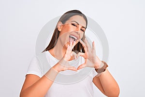 Portrait of beautiful and young brunette woman standing over isolated white background smiling in love doing heart symbol shape