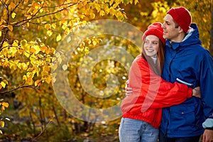 Portrait of a beautiful young caucasian couple standing in autumn forest and hugging