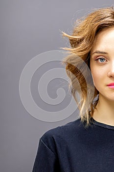 Portrait of a beautiful young caucasian red-haired woman with short wavy hairstyle smiling and looking at camera on dark