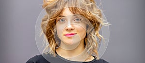 Portrait of a beautiful young caucasian red-haired woman with short wavy hairstyle smiling and looking at camera on dark