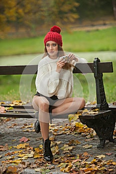Portrait of a beautiful young Caucasian sensual woman with a red cap ,white pullover and black boots in autumn park
