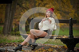 Portrait of a beautiful young Caucasian sensual woman with a red cap ,white pullover and black boots in autumn park