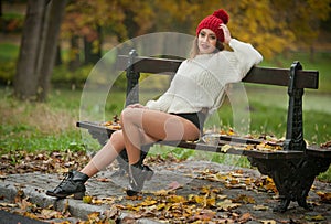 Portrait of a beautiful young Caucasian sensual woman with a red cap ,white pullover and black boots in autumn park