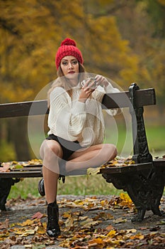 Portrait of a beautiful young Caucasian sensual woman with a red cap ,white pullover and black boots in autumn park