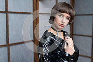 Portrait beautiful young caucasian woman in black patent suit with one hand