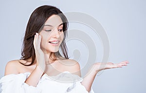 Portrait of beautiful young caucasian woman with healthy clean skin presenting something on her hand.