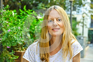 Portrait of beautiful young caucasian woman with long blond hair blue eyes sitting in European American street cafe