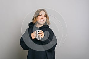 Portrait of beautiful young charming woman holding cup of coffee or tea over grey background