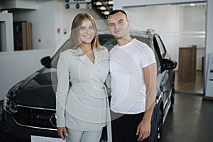 Portrait of beautiful young couple happy after buying new car from car showroom. Woman hus her man and glad