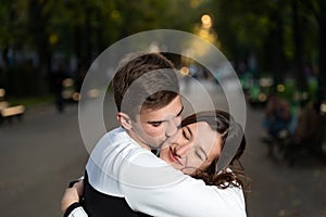 Portrait of beautiful young couple in park. Guy gently kissed the girls cheek