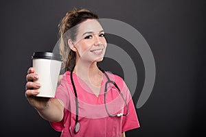 Portrait of beautiful young doctor offering takeaway coffee photo