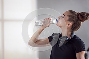 Portrait of beautiful young fit woman drinking water during traning in the gym