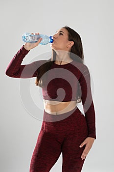 Young beautiful girl with mineral water isolated on white , portrait of beautiful young fit woman drinking water during traning