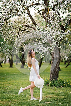 Portrait of a beautiful young girl in a blooming apple orchard in spring