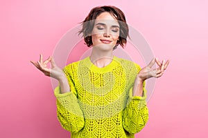 Portrait of beautiful young girl closed eyes balancing meditation yoga om position wear yellow jumper isolated on pink