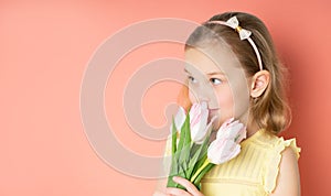 Portrait of a beautiful young girl in dress holding big bouquet of tulips isolated over pink background