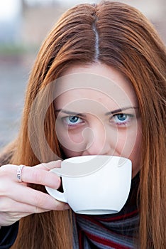 Portrait of a beautiful young girl drinking coffee outdoors