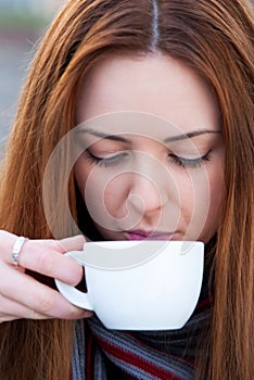 Portrait of a beautiful young girl drinking coffee outdoors loo