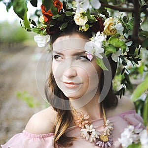 Portrait of a beautiful young girl in a flying bride tender pink dress on a background of green field, she laughs and poses with a