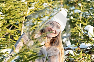 Portrait of a beautiful young girl in a fur coat and hat on the background of the winter forest