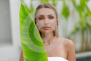 Portrait of a beautiful young girl with a green leaf. Spa treatments